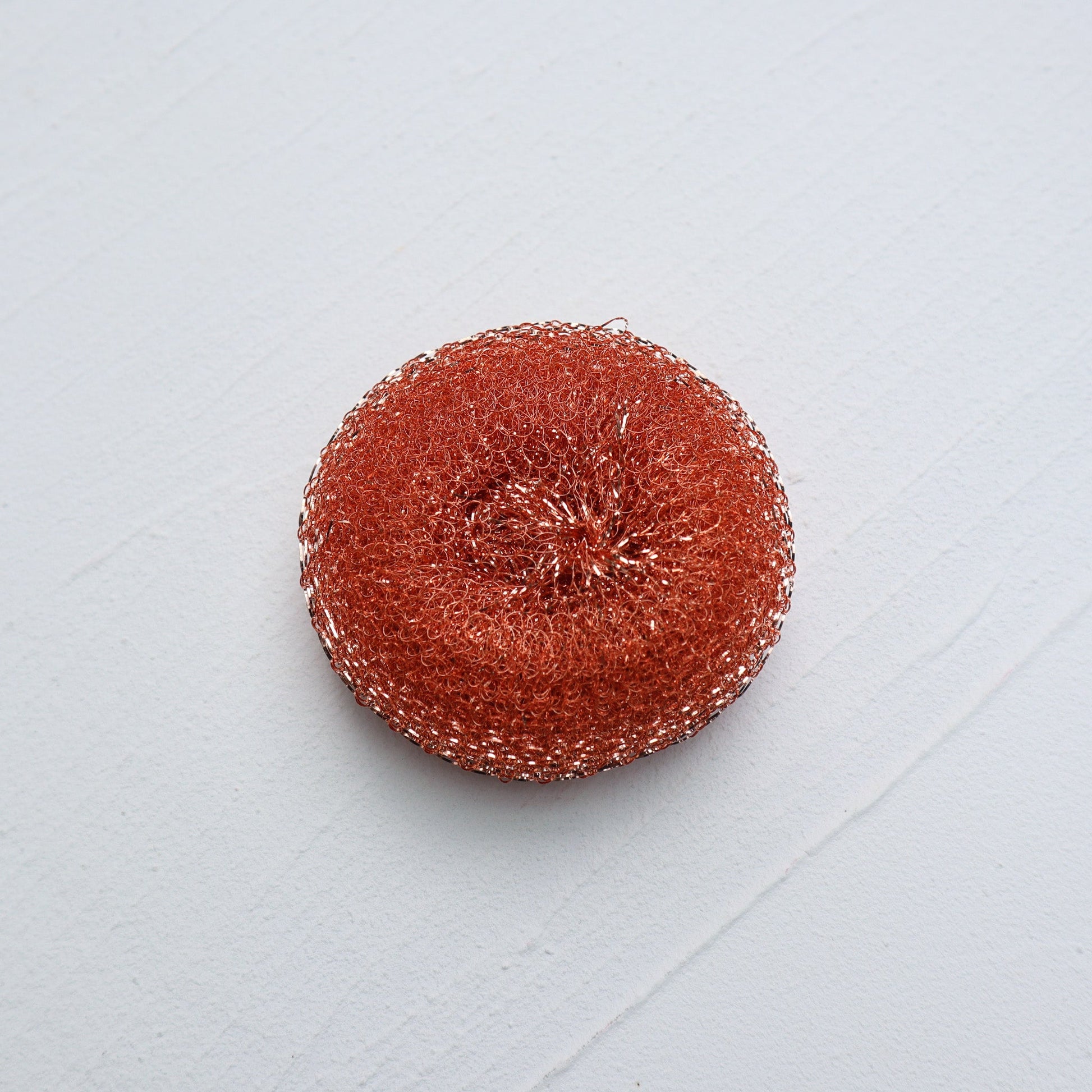 Round red scrubbie on a light gray background