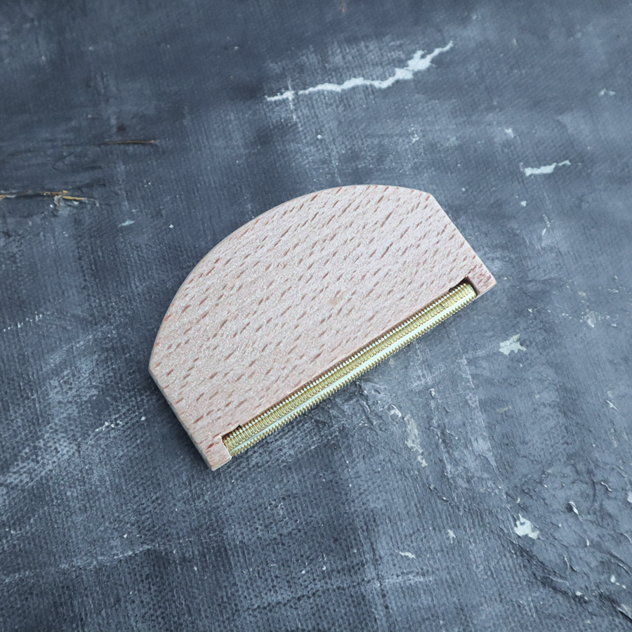Half-circle pouch with textured surface and gold zipper on a textured gray background